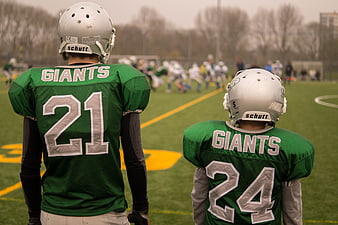 Two young football players watching game from sidelines