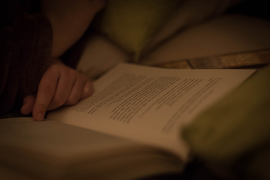 Close-up of hand reading book in dim light