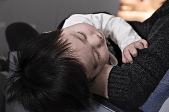 Close-up of sleeping baby held by parent