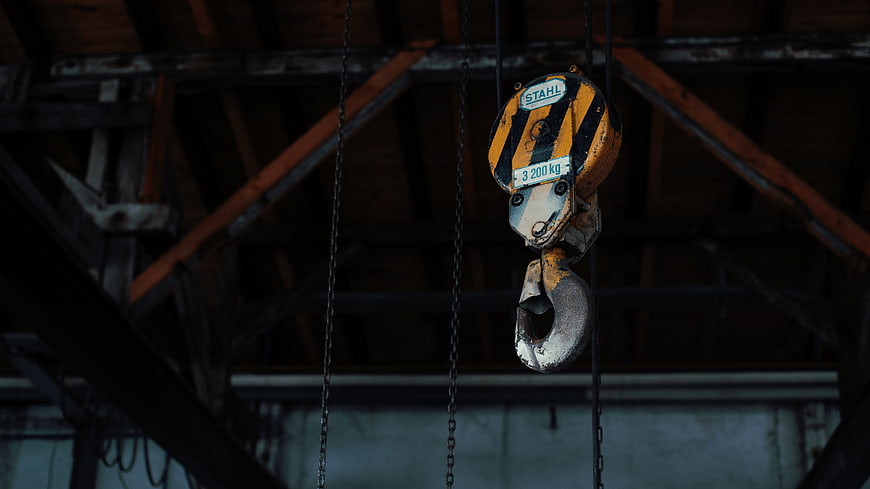 Industrial Crane Hook Hanging in Dark Warehouse
