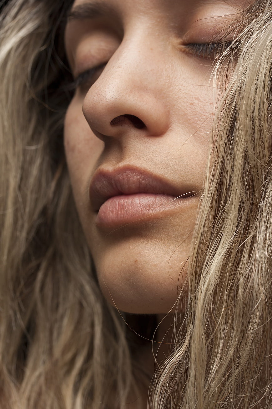 Close-up portrait of a young woman with closed eyes and natural skin texture