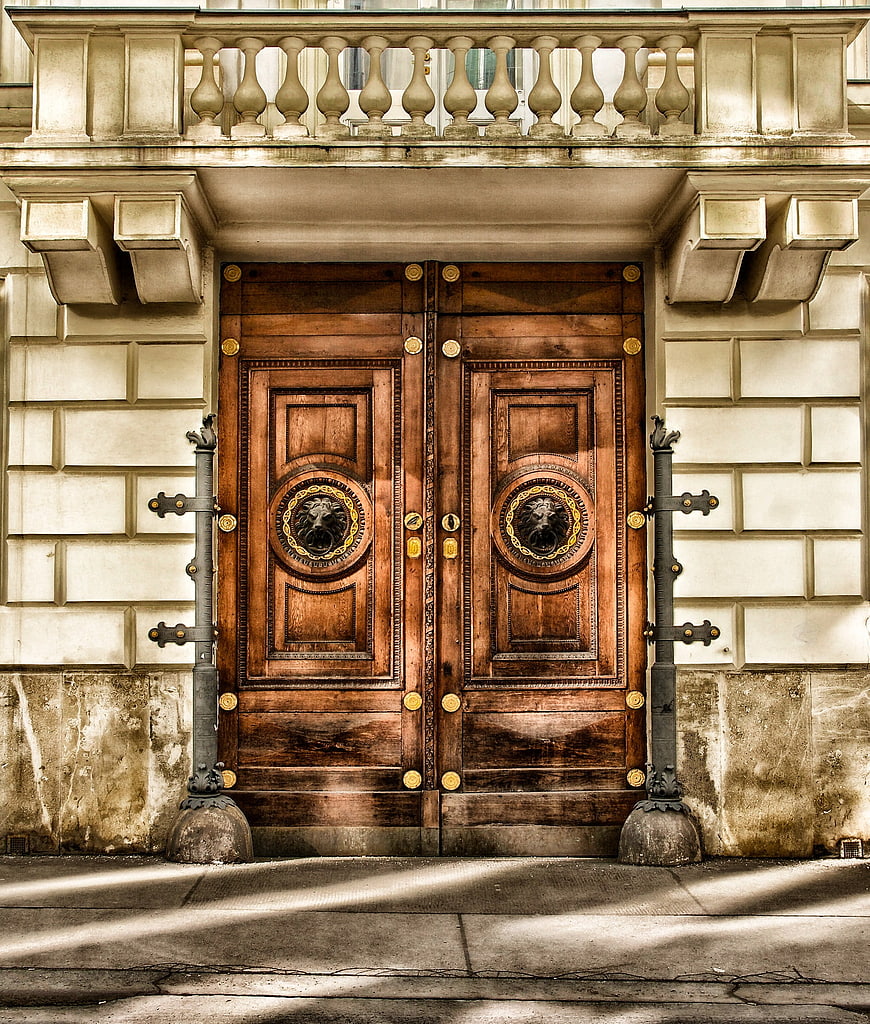 Ornate wooden double doors with lion head knockers on historic building facade
