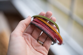 Hand holding colorful leather bracelets with embossed patterns