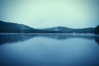 Serene Misty Lake Landscape with Forested Hills at Dawn