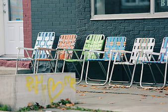 Colorful striped lawn chairs lined up against a brick wall