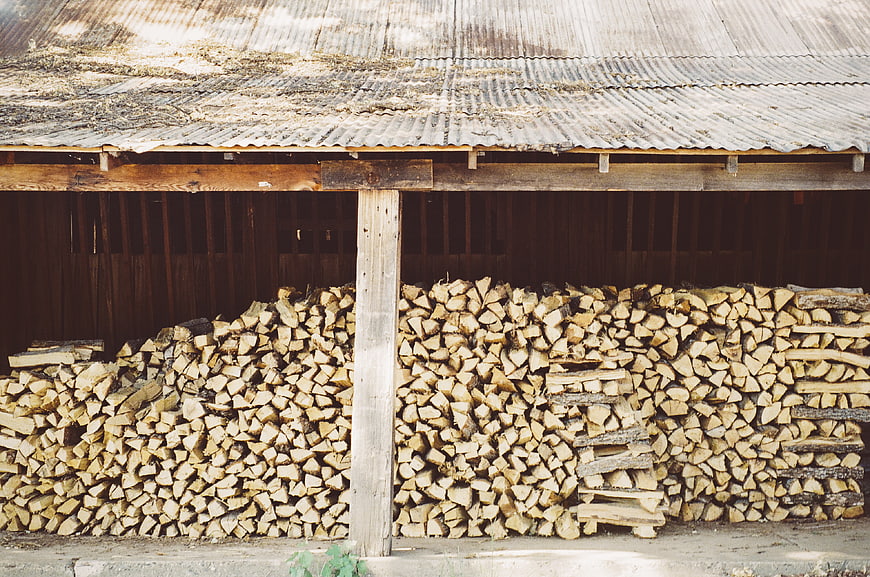 Stacked firewood under rustic corrugated metal roof