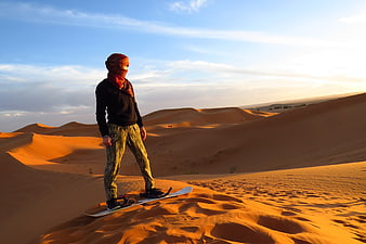 Man Sandboarding on Golden Sand Dunes in Morocco Desert
