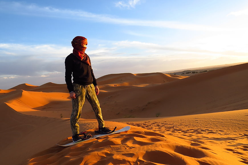 Man Sandboarding on Golden Sand Dunes in Morocco Desert