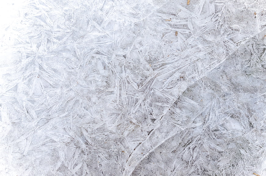 Close-up of intricate frost patterns on frozen ice surface
