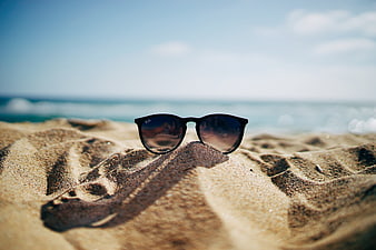Black Sunglasses Resting on Sand at Sunny Beach