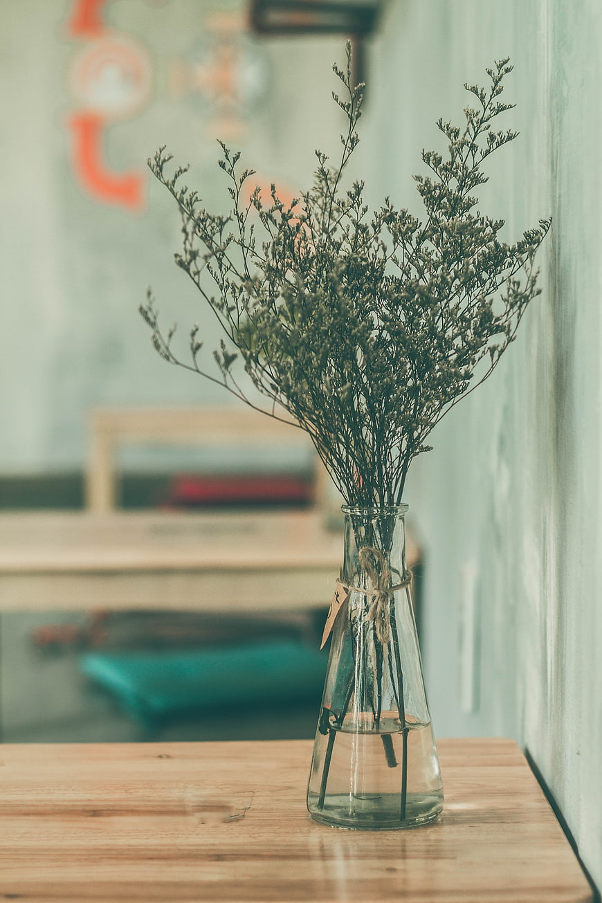 Dried flowers in glass vase on wooden table