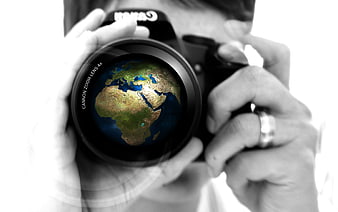 Photographer holding camera with globe reflection in lens