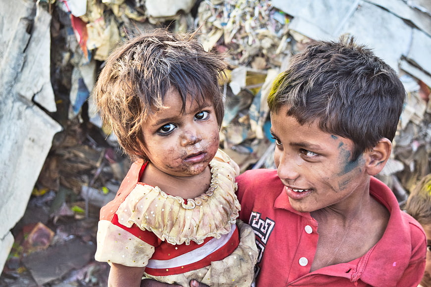 Two young children in slums with colorful powder on faces