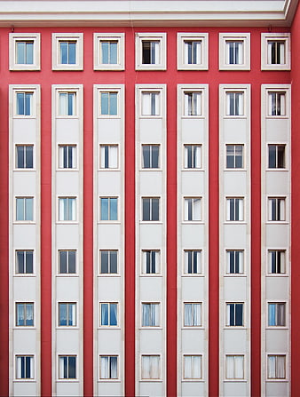 Red apartment building facade with symmetrical white windows