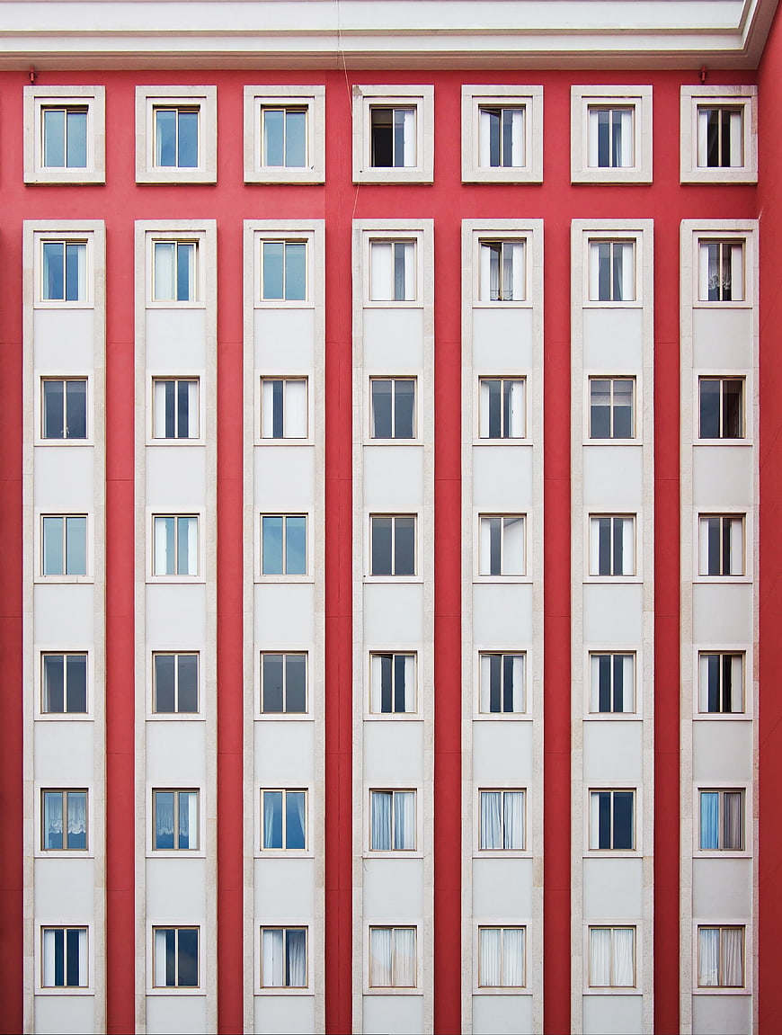 Red apartment building facade with symmetrical white windows