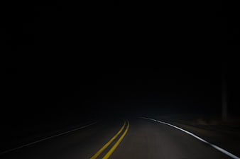 Dark winding road at night with yellow lines