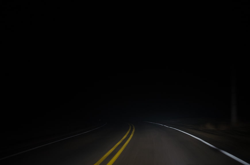 Dark winding road at night with yellow lines