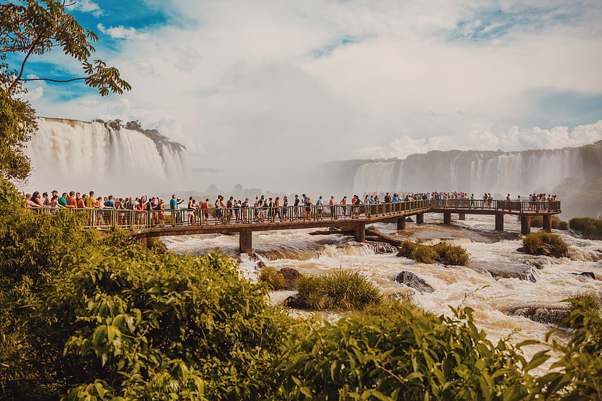 Tourists on wooden walkway viewing massive waterfalls