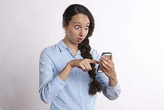 Surprised woman with long braid using smartphone