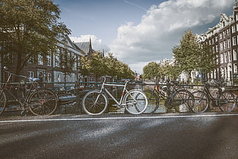 Bicycles Parked Along Amsterdam Canal Bridge