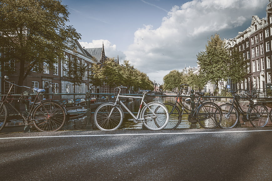Bicycles Parked Along Amsterdam Canal Bridge