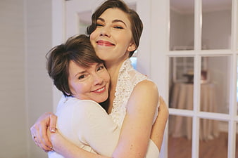 Happy bride hugging mother in white lace dress