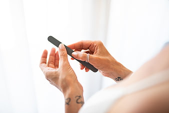 Woman Filing Nails with Black File Close Up
