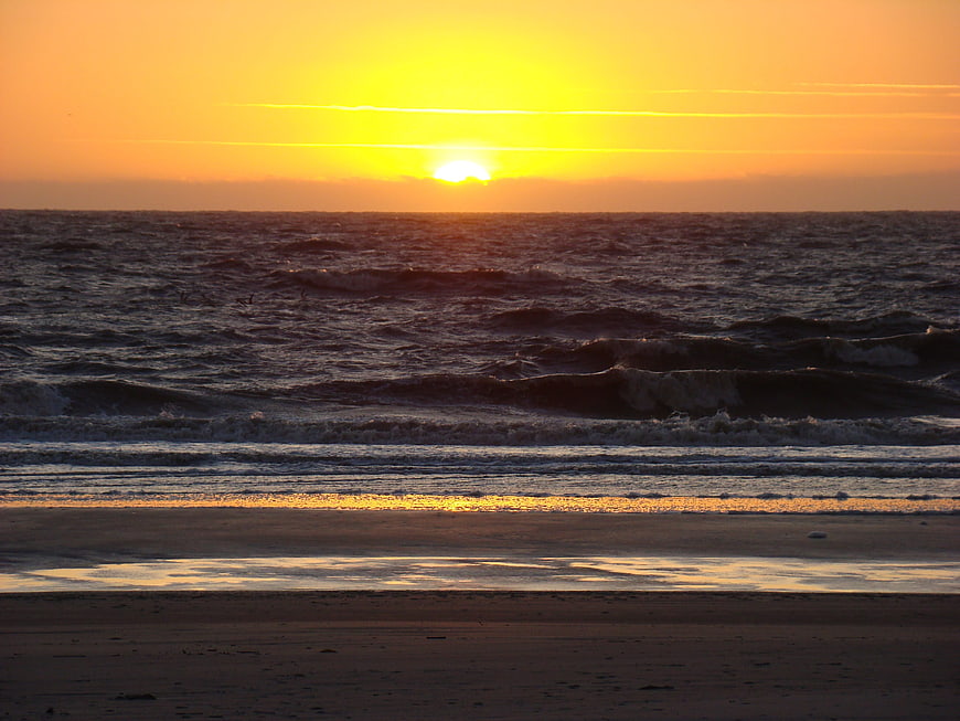 Golden Sunset Over Choppy Ocean Waves on Sandy Beach