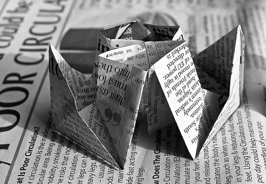 Black and white origami heart on newspaper