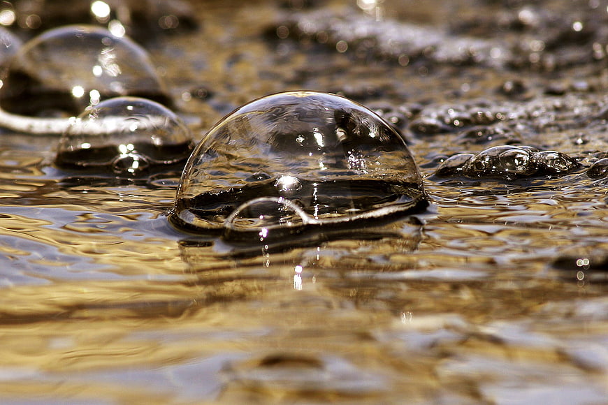 Close-up of water bubbles on a golden reflective surface