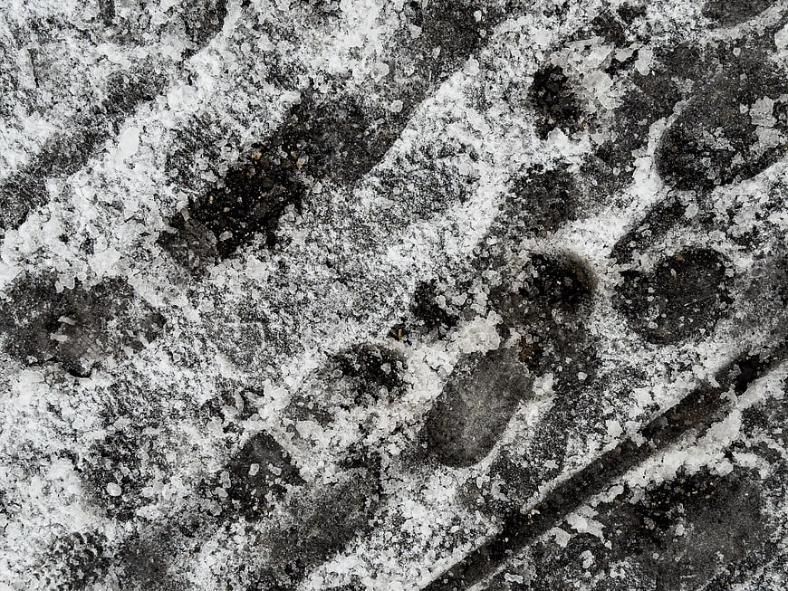 Close-up of tire tracks in icy snow on asphalt
