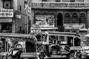 Black and white street scene with auto rickshaws in India