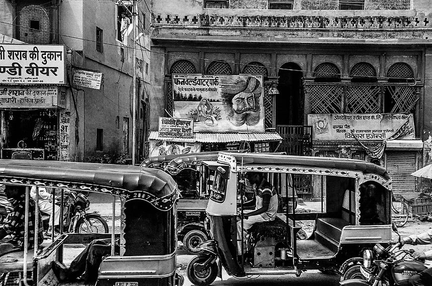 Black and white street scene with auto rickshaws in India