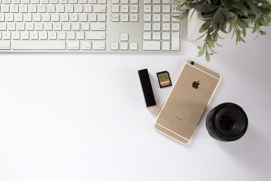 Flat Lay Workspace with Smartphone, Keyboard, and Camera Lens