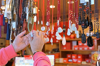 Hands Selecting Jade Pendants at Asian Jewelry Market Stall