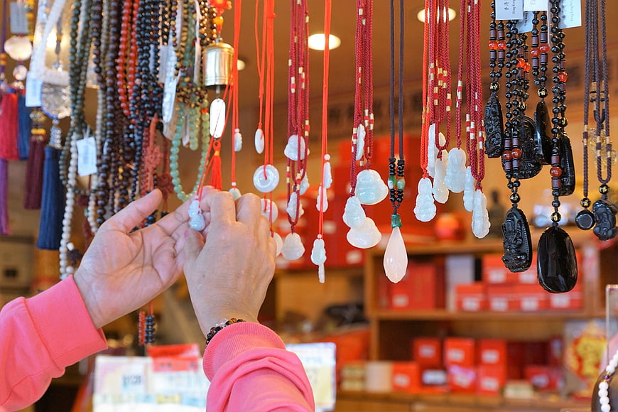 Hands Selecting Jade Pendants at Asian Jewelry Market Stall