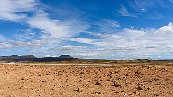 Vast arid landscape with rocky terrain and blue sky