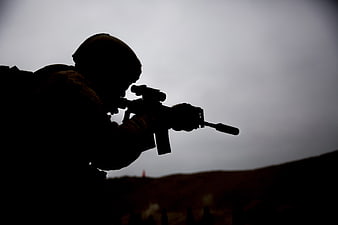 Silhouette of soldier aiming rifle during military training exercise