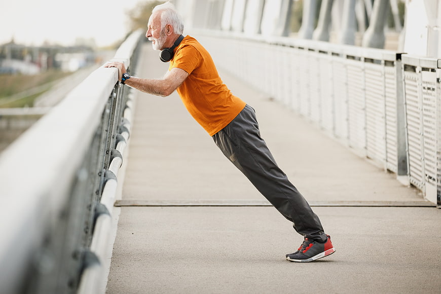 Senior man doing incline push-ups on bridge railing