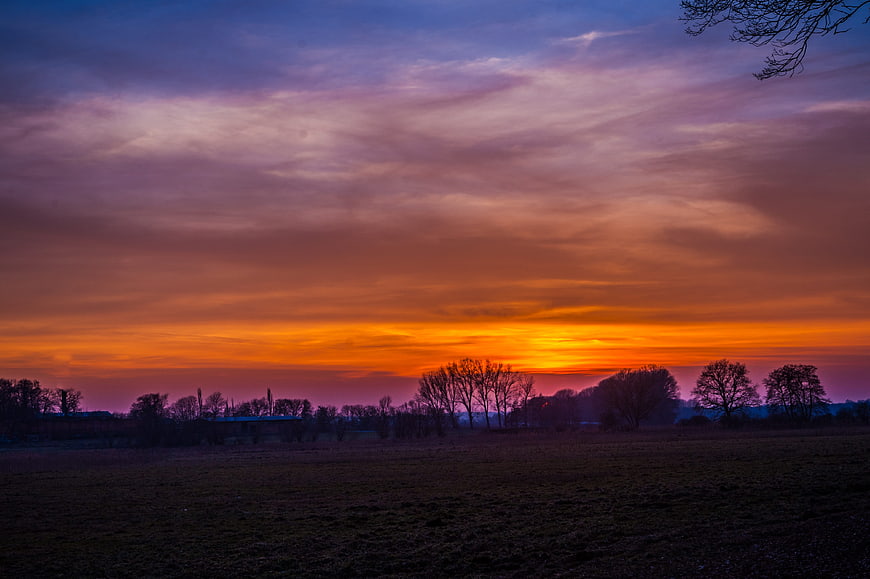Vibrant orange and purple sunset over rural landscape