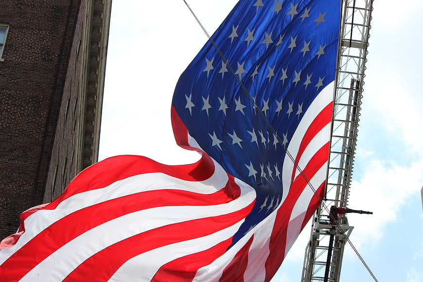 Large American Flag Waving in Wind Against Sky