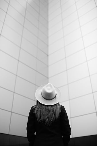 Woman in Fedora Hat Looking Up at White Tiled Wall