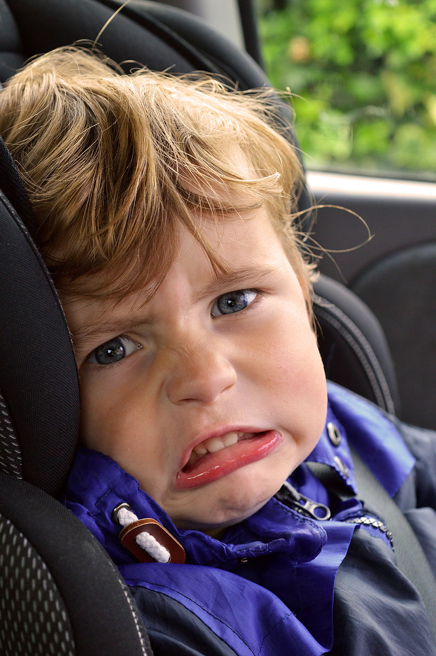 Close-up of a young boy making a funny disgusted face in a car seat