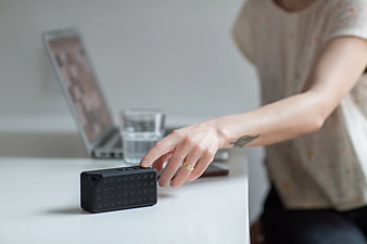 Woman Hand Pressing Button on Portable Bluetooth Speaker