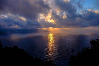 Dramatic Sunset Over Ocean with Sunbeams and Clouds