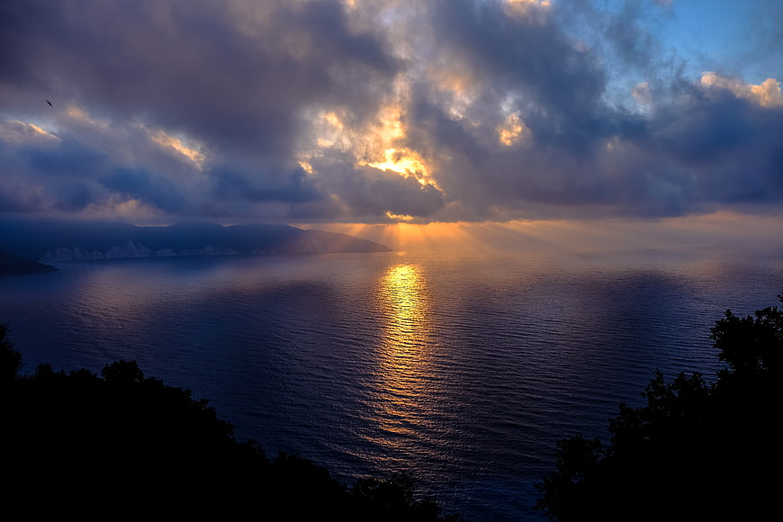 Dramatic Sunset Over Ocean with Sunbeams and Clouds