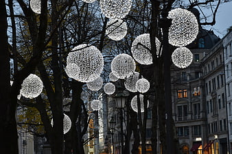 Glowing spherical Christmas lights hanging in city trees