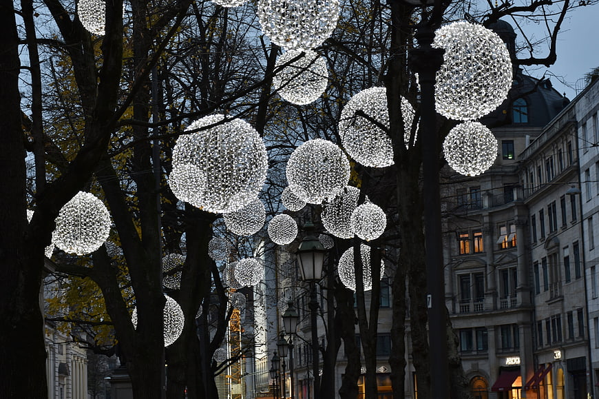 Glowing spherical Christmas lights hanging in city trees