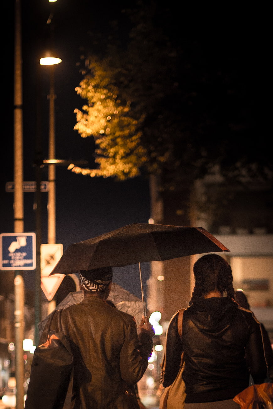 Couple Walking Under Umbrella in City Rain at Night