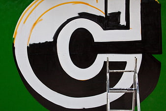 Close-up of large black and white graffiti letter on green wall
